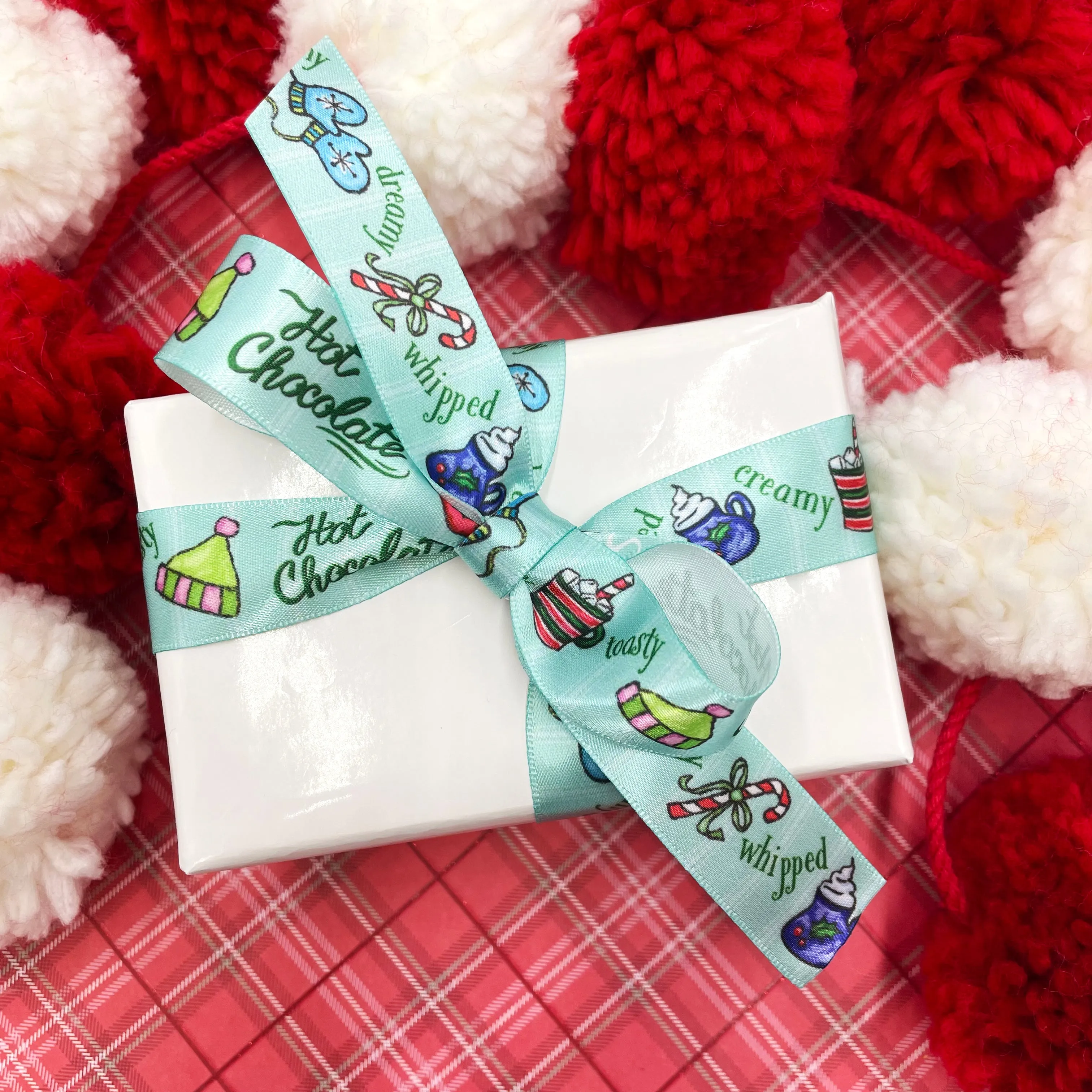 Hot Chocolate Ribbon with mugs, hats, mittens and candy canes on a blue and white striped background printed on 7/8" white satin